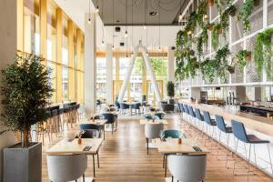 a restaurant with tables and chairs and plants at Holiday Inn Express Amsterdam - North Riverside by IHG in Amsterdam