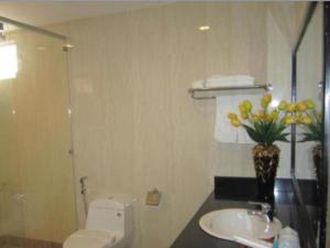 a bathroom with a toilet and a sink and a vase of flowers at Song Thu hotel in Da Nang