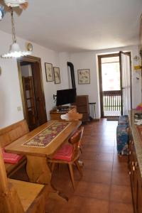 ein Wohnzimmer mit einem Tisch, Stühlen und einem TV in der Unterkunft Appartamento Alto Cordevole in Colle Santa Lucia