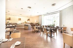 una sala da pranzo con tavoli e sedie e un ristorante di Novum Hotel Madison Düsseldorf Hauptbahnhof a Dusseldorf