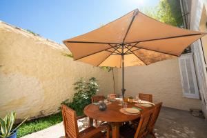 a wooden table with an umbrella on a patio at Roma Divine home cinéma et jardin in Nîmes