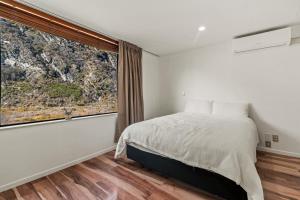 een slaapkamer met een bed en een groot raam bij Snowy Peaks - Queenstown Holiday Apartment in Queenstown