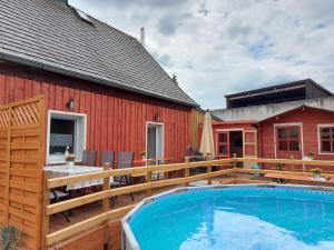 eine Holzterrasse mit einem Pool und einem Haus in der Unterkunft Ferienhaus Kleiner Waldstein in Weißdorf