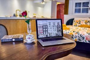 einen Laptop auf einem Holztisch mit einer Kaffeetasse in der Unterkunft Studio next to Skinny Bridge near Rembrandtsquare in Amsterdam