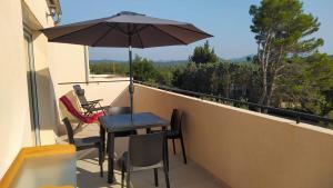 einen Tisch und Stühle auf einem Balkon mit Sonnenschirm in der Unterkunft Les Bosquets JOLY in Montauroux
