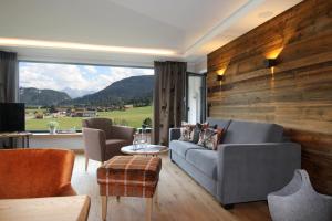 a living room with a couch and a large window at Bergzauber Alpin Suites - Skipiste - Private Sauna in Bolsterlang
