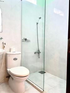 a bathroom with a toilet and a glass shower at T's House Motel in Ấp Bình Hưng