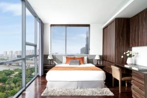 a bedroom with a bed and a desk and a large window at Oakwood Hotel & Apartments Saigon in Ho Chi Minh City