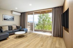 ein Wohnzimmer mit einem Sofa und einem großen Fenster in der Unterkunft Kensington Resort Gyeongju in Gyeongju