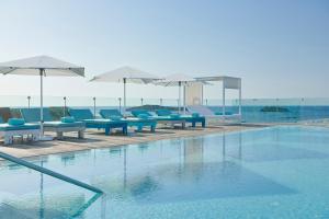a swimming pool with blue chairs and umbrellas at Iberostar Selection Santa Eulalia Adults-Only Ibiza in Santa Eularia des Riu