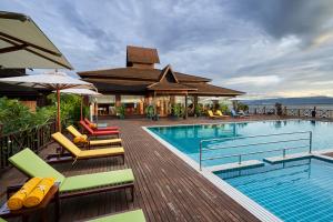 a swimming pool with lounge chairs and an umbrella at KMA Inle Hotel in Nyaungshwe Township