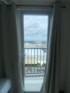 uma janela com vista para o oceano a partir de um quarto de hotel em 1BR unit in South Residence Las Pinas with Wifi & Netflix em Manila