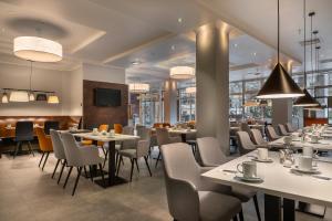 un restaurante con mesas, sillas y TV en Select Hotel Wiesbaden City en Wiesbaden