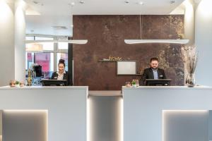 two people sitting at a counter in a office at Select Hotel Wiesbaden City in Wiesbaden
