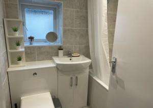 a bathroom with a sink and a toilet and a window at 2 bedroom serviced apartment # in London