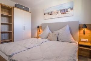 een slaapkamer met een bed met witte lakens en kussens bij Fewo Backbord Haus Borkum Whg 5 in Hooksiel