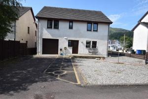 a white house with a garage in a driveway at Ridgeview Villa - Partial loch view in Lochgoilhead