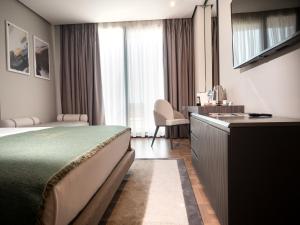 a hotel room with a bed and a desk and window at La Brisa Boutique Hotel in Dhërmi