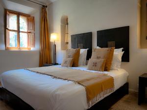 a bedroom with a large white bed with pillows at Maidan El Arsa in Oulad Mazoug