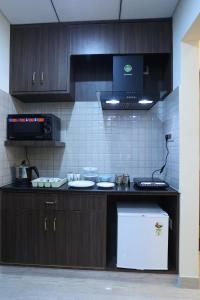 eine Küche mit Holzschränken und einem weißen Kühlschrank in der Unterkunft Minas Manor in Tiruchchirāppalli