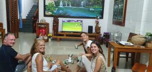 eine Gruppe von Menschen, die um einen Tisch sitzen und ein Videospiel spielen in der Unterkunft Tam's Homestay in Phong Nha