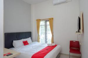 a bedroom with a bed with a red pillow and a window at RedDoorz @ Kratonan Solo in Solo