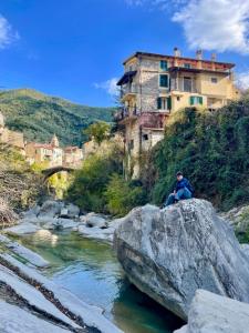 a person sitting on a rock near a river at Casa Celestine in Via Orsini Isolabona Liguria Italy Sleeps 5 in Isolabona