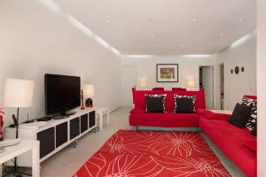 een woonkamer met een rode bank en een flatscreen-tv bij Large apartment in Vale do Lobo in Almancil