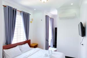 Kampot Coco Guest House في كامبوت: غرفة نوم بسرير والستائر زرقاء وتلفزيون