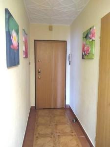 a hallway with a wooden door and paintings on the walls at Apartament z widokiem na Zatokę, Hel, Port i lasy in Gdańsk