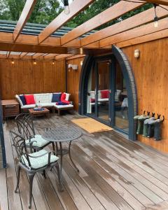a patio with a table and chairs on a wooden deck at Bedrule Old Manse Glamping in Hawick