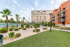 un parque con palmeras y un edificio en Moderno apartamento con Piscina y Parking, en Granada