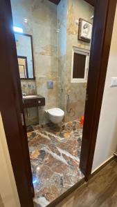 a bathroom with a toilet and a marble floor at Kafal Gates in Lansdowne