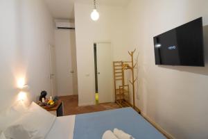 La Dimora di Artemide B&B في نابولي: غرفة نوم بسرير وتلفزيون بشاشة مسطحة