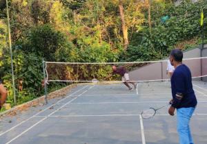 a couple of people playing tennis on a tennis court at Wayanad Village Resort in Koroth