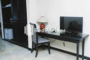 einen Schreibtisch mit einem TV und einem Stuhl in einem Zimmer in der Unterkunft Hotel Yasmin Makassar Mitra RedDoorz in Makassar