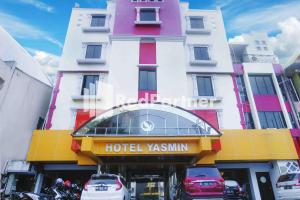 a hotel xiamen building with cars parked in front of it at Hotel Yasmin Makassar Mitra RedDoorz in Makassar
