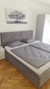 1 cama en un dormitorio con un árbol en la pared en Apartmani Marčetić en Slavonski Brod