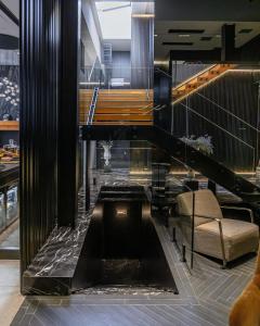 a lobby with a black piano and a chair at Hotel MANAMI in Prishtinë