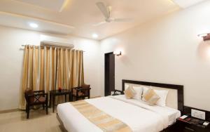 Hotel The Sudesh في رايبور: غرفة نوم بسرير ابيض كبير وطاولة