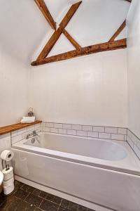 a white bath tub in a bathroom with wooden beams at Guest Homes - Snodsbury Barn in Upton Snodsbury