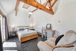 a bedroom with a bed and two chairs and a couch at Guest Homes - Snodsbury Barn in Upton Snodsbury