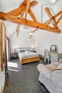 a bedroom with a bed and a desk and a couch at Guest Homes - Snodsbury Barn in Upton Snodsbury