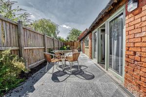 a patio with a table and chairs and a fence at Guest Homes - Snodsbury Barn in Upton Snodsbury