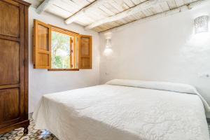 エル・パルマルにあるCasita-estudio El Castañoの白いベッドルーム(ベッド1台、窓付)
