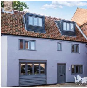 a white house with windows and a roof at Grade II Listed 3 Bedroom Cottage With Free Parking in King's Lynn