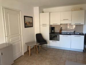 a kitchen with white cabinets and a table and a chair at Citronnier Monaco Sea View in Beausoleil