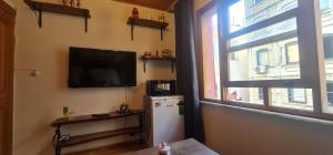 a room with a television and a refrigerator and a window at Galata Duplex Apt. *Balcony* 1 min to Metro Stn. in Istanbul
