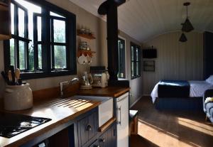 una cocina con fregadero y una cama en una habitación en Large Luxury Shepherds Hut with Hot Tub nr Bath en Bristol