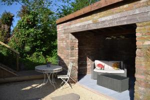 een patio met een tafel, een stoel en een bakstenen muur bij Large Luxury Shepherds Hut with Hot Tub nr Bath in Bristol